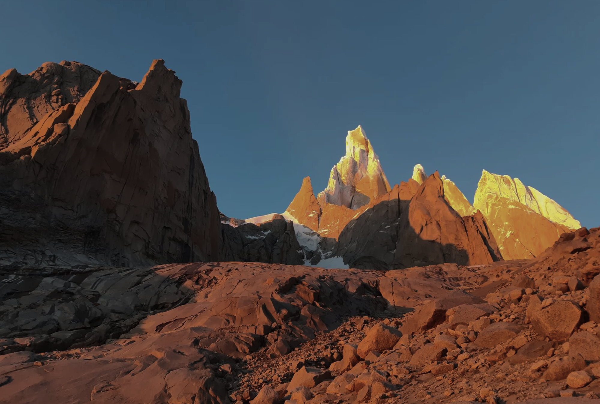 Patagonian peaks at sunrise with granite towers and snow-covered mountains in the distance.