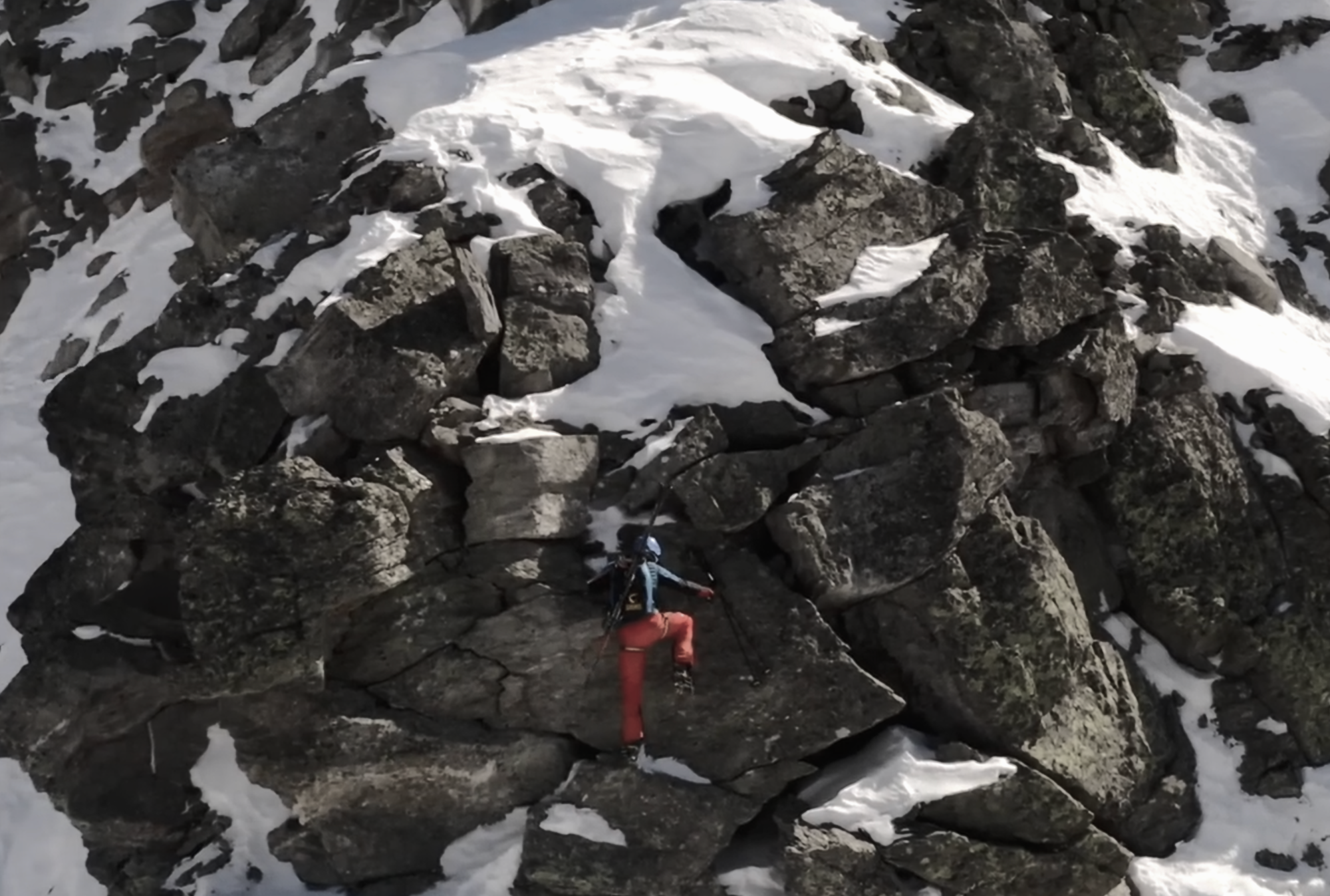 Denis Trento moving through rocky alpine terrain in winter conditions.