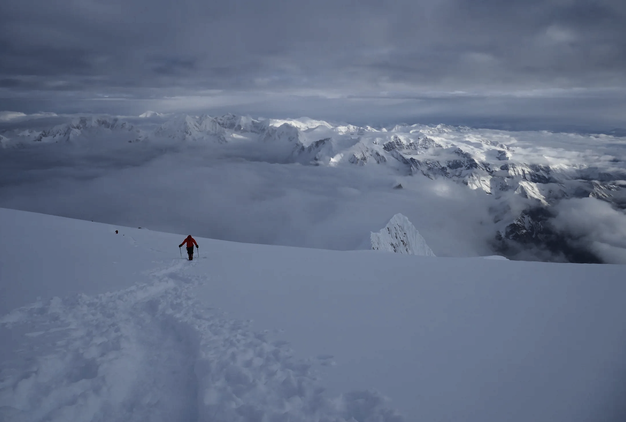 Mountaineer crossing a snow-covered high-altitude ridge on Manaslu.
