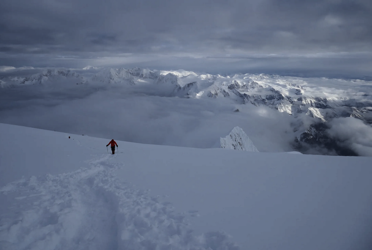 Mountaineer crossing a snow-covered high-altitude ridge on Manaslu.