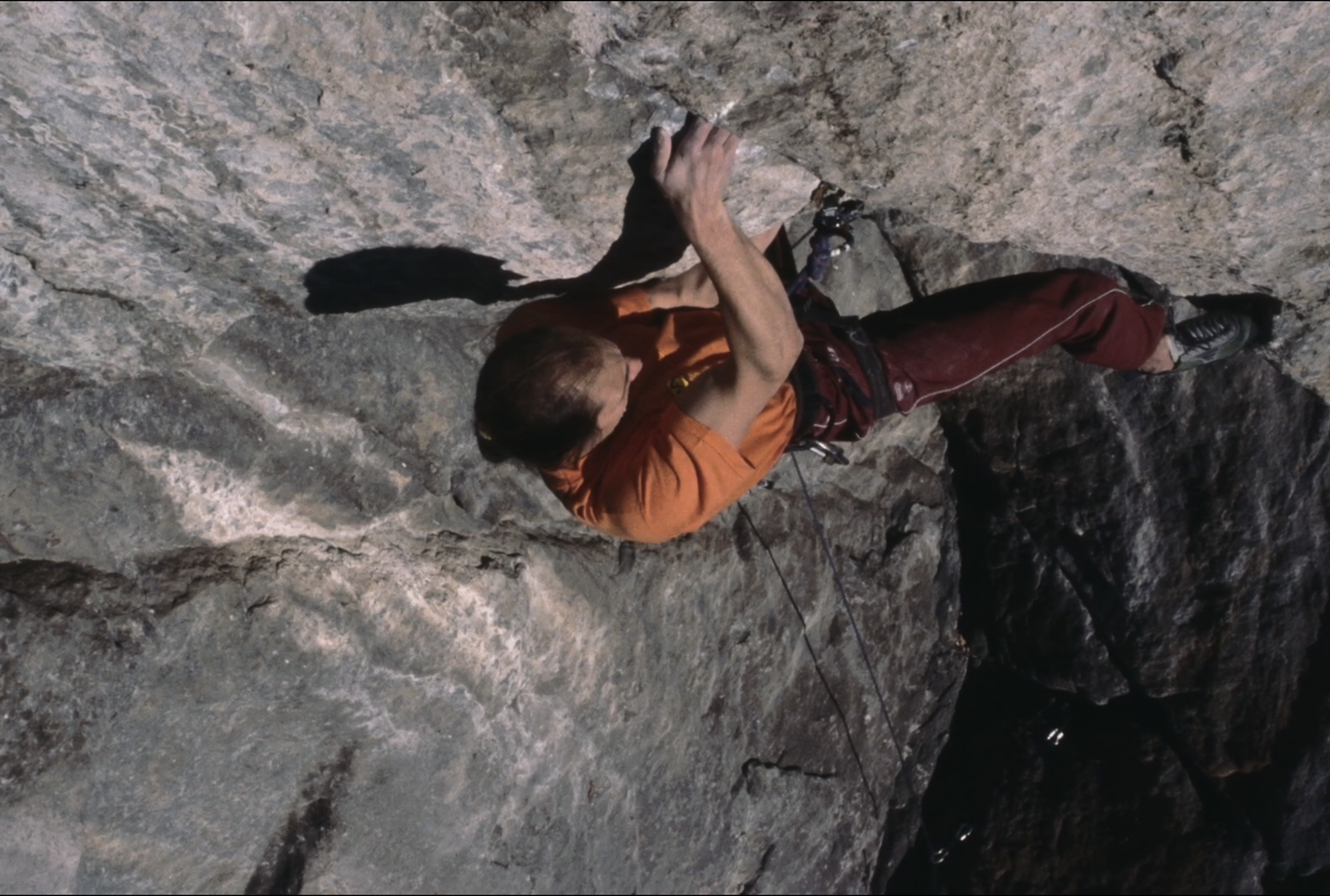 Climber on steep granite terrain during the ascent of Socialmente Inutile in Val Masino, Italy.