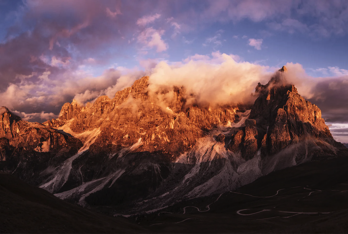 Sunlit mountain landscape beneath dramatic clouds in the Dolomites, Italy.