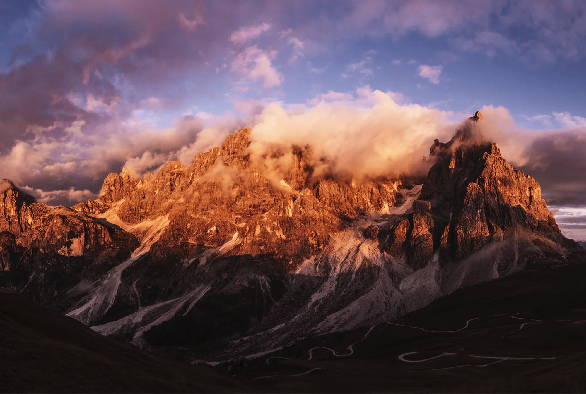 Sunlit mountain landscape beneath dramatic clouds in the Dolomites, Italy.