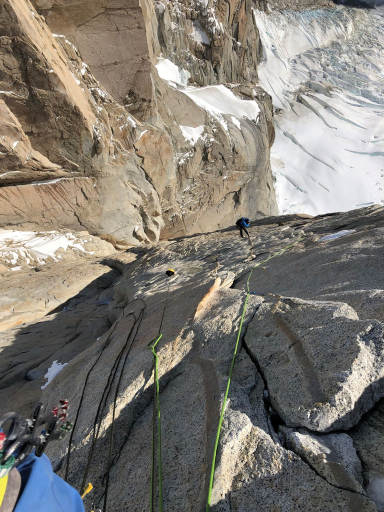 Climber progressing across steep granite slabs on Cerro Torre