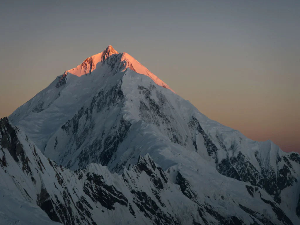 Alpenglow on a steep snow-covered Karakoram summit ridge.