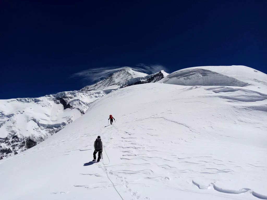 Climbers crossing a glaciated ridge during a Karakoram ascent.