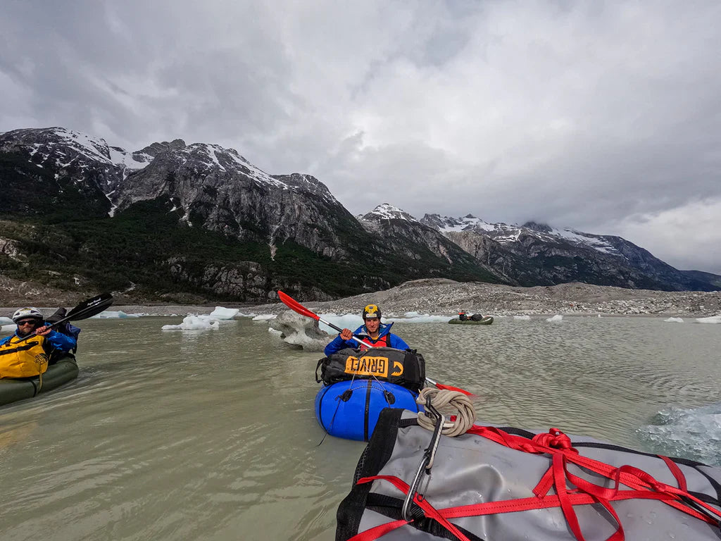 Expedition team crossing glacial water with packrafts in Patagonia