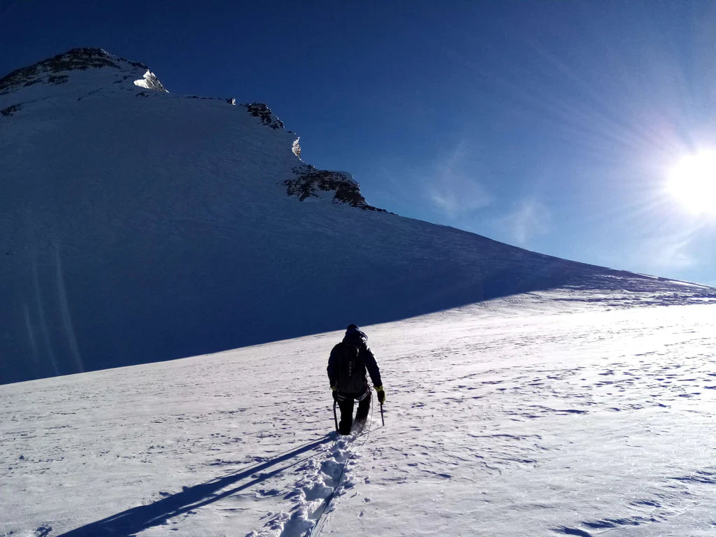 Climber ascending a broad snowfield during a Karakoram expedition.