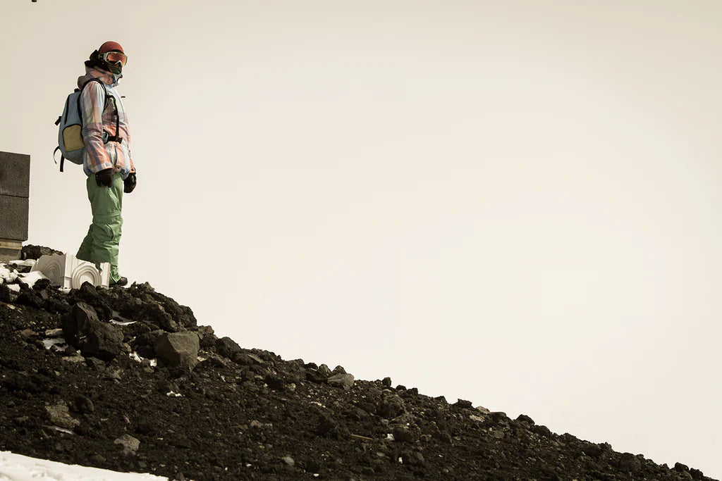 Skier standing on a snowless alpine slope affected by climate change