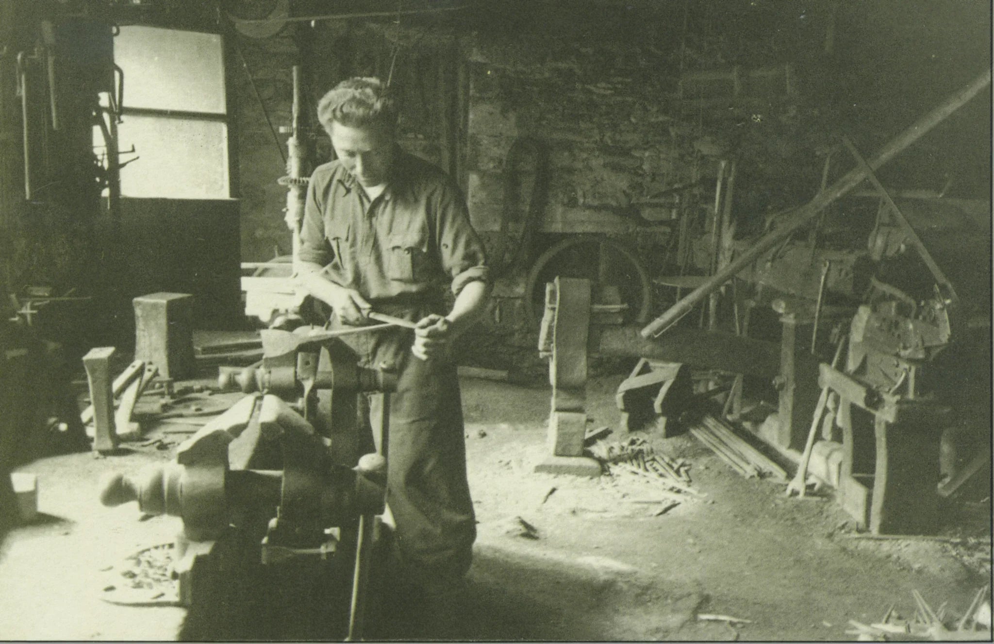 Grivel blacksmith working metal inside a historic alpine forge workshop.