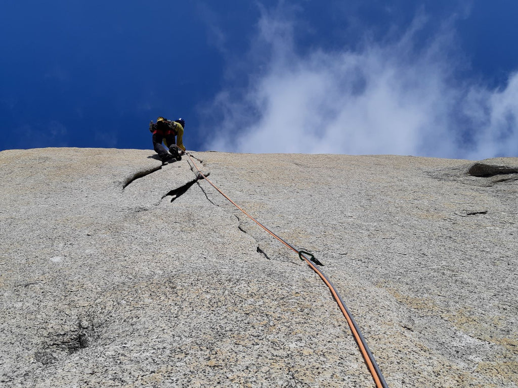 Climber ascending a granite slab on a roped route in Patagonia.