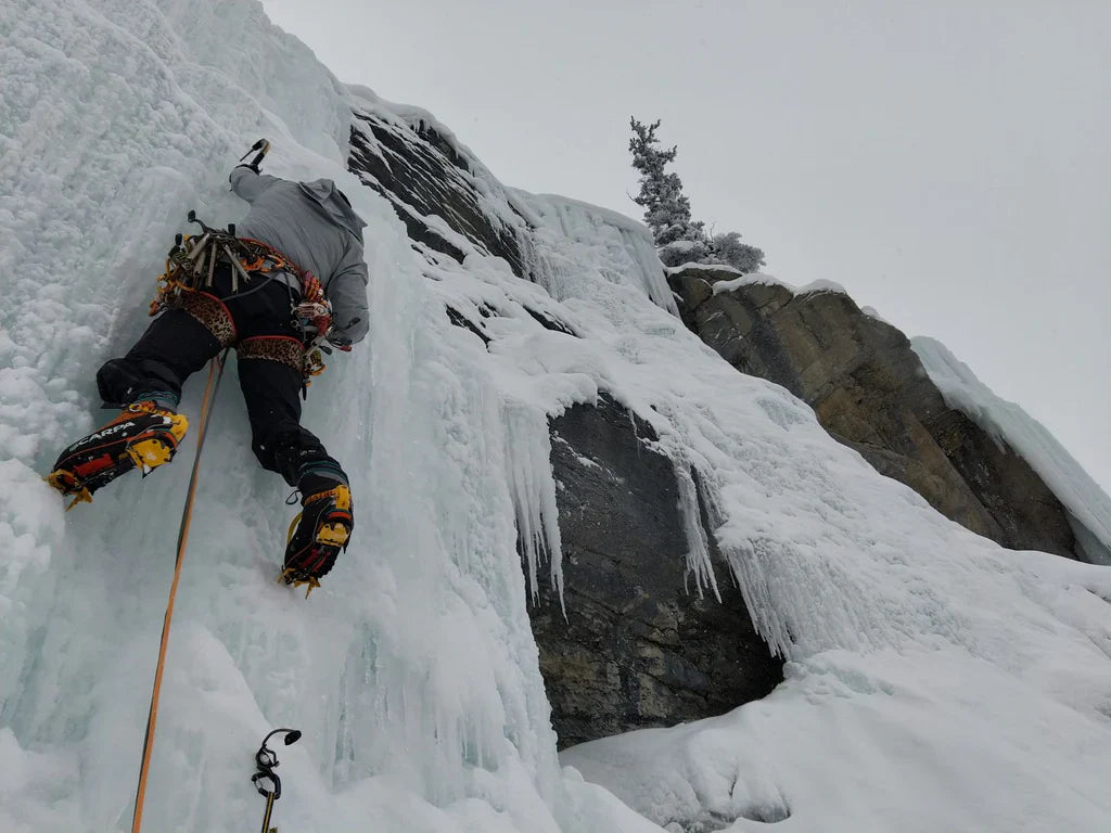 Charlotte Barré ascending steep ice with frozen rock and snow around the route.