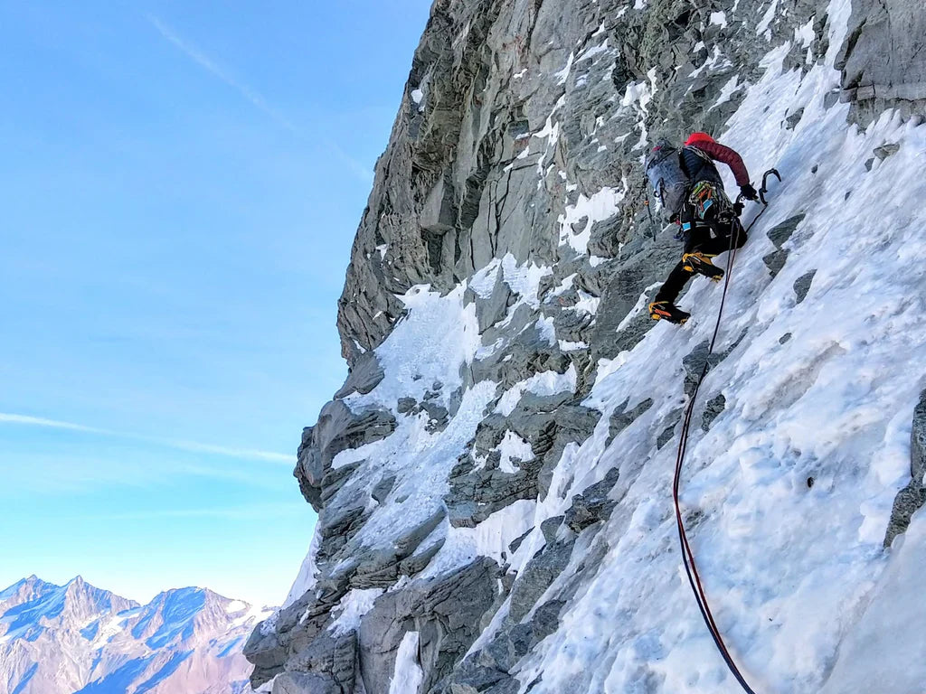 Climber ascending steep snow and rock on the Bonatti Route.