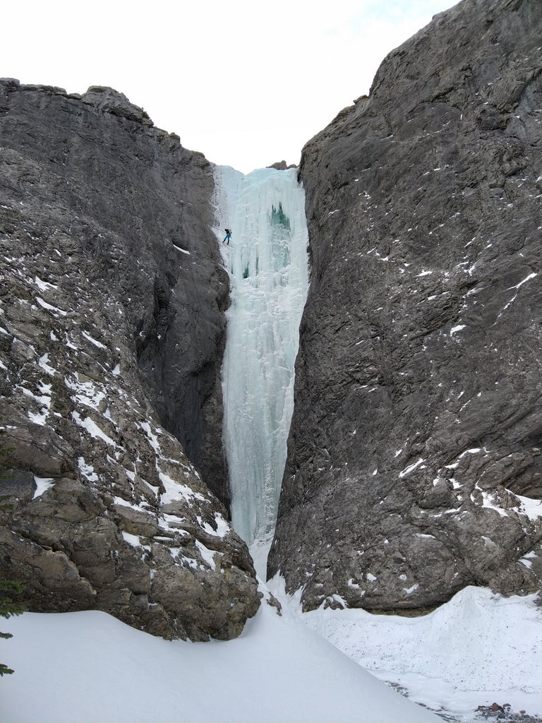 Tall frozen waterfall between rock walls in the Canadian Rockies.