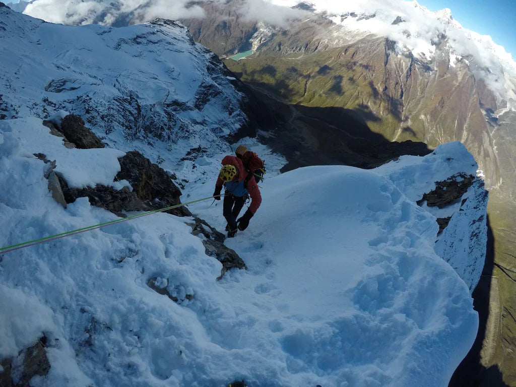 Mountaineer ascending steep snow and rock terrain on Pangpoche.