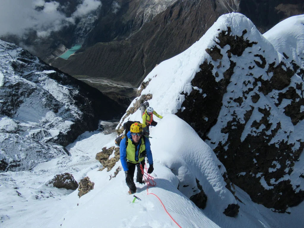 Roped team climbing an exposed snow ridge above the valley during the Pangpoche attempt.