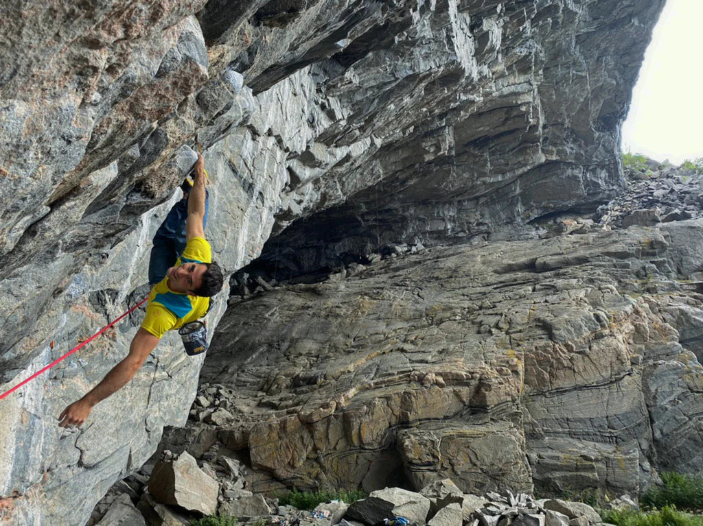 Marcello Bombardi climbing exposed granite terrain above the Norwegian landscape.