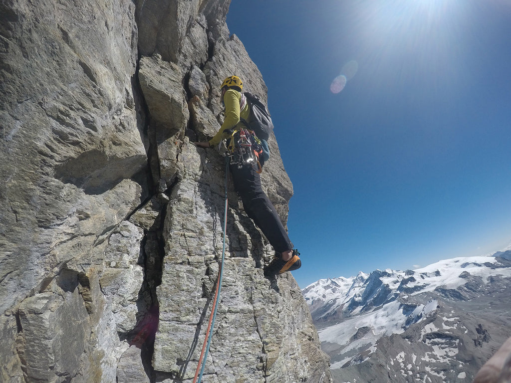 Michele Cazzanelli leading technical rock climbing pitches on the Scudo del Cervino beneath clear alpine skies.