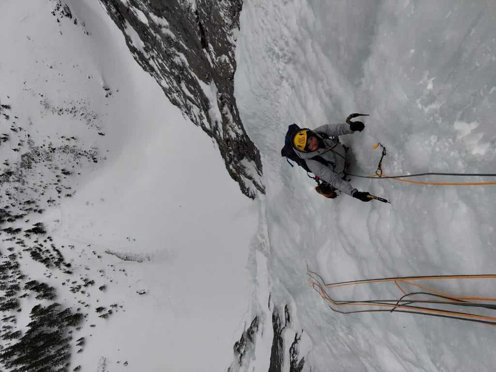 Ice climber on a steep frozen waterfall in winter conditions.