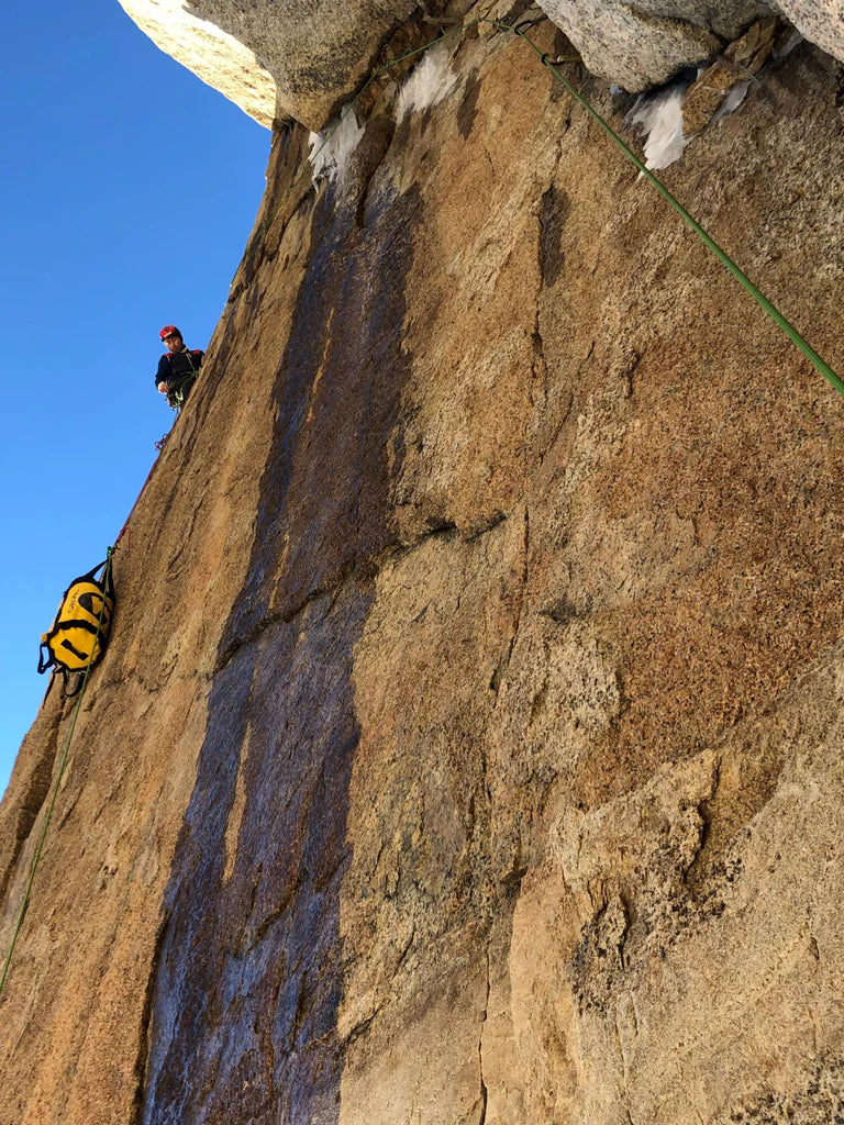 Climber hauling equipment on steep granite terrain during the ascent of La Norte