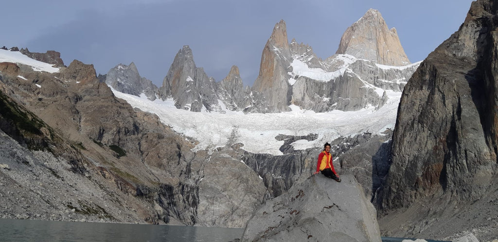 Silvia Loreggian sitting on a boulder below the granite towers of Patagonia.