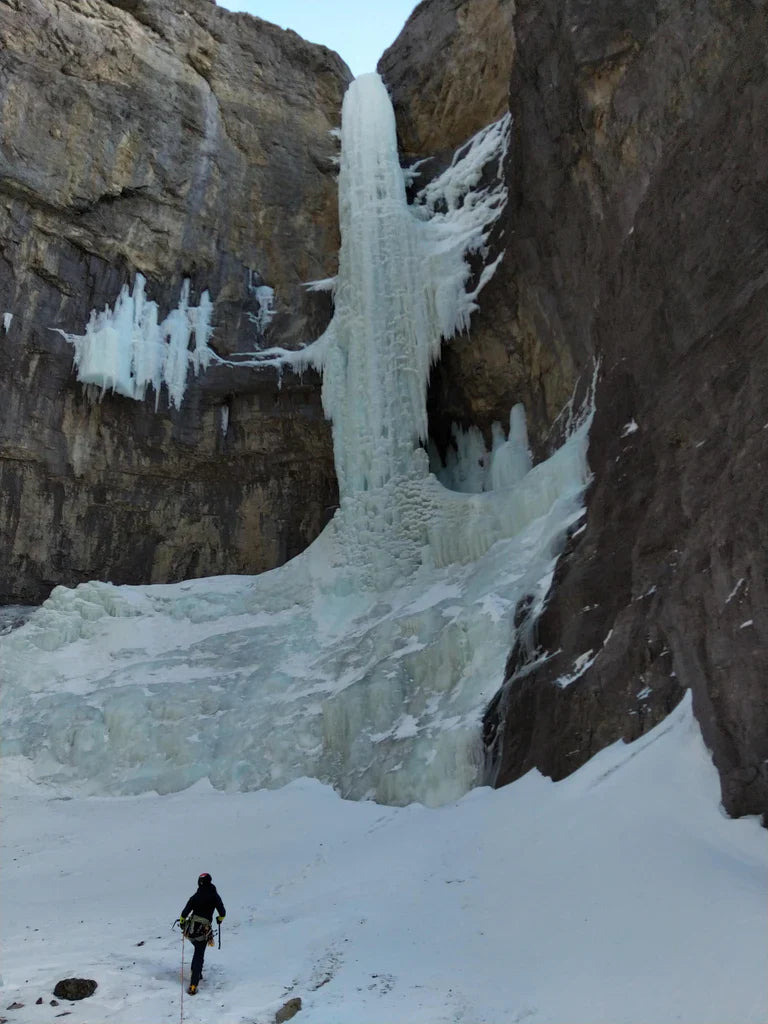 Climber approaching a large frozen waterfall in the Canadian Rockies